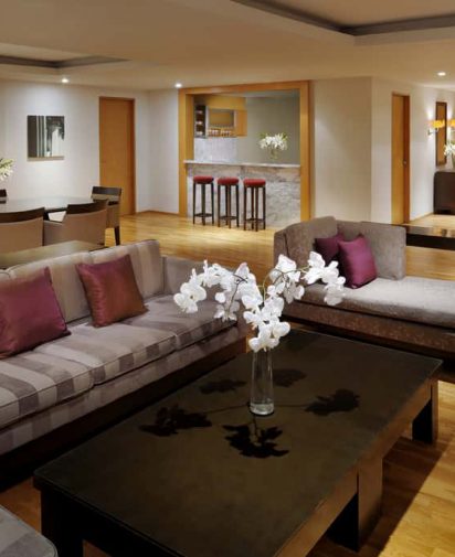living room with grey couches brown coffee table and stools in the background