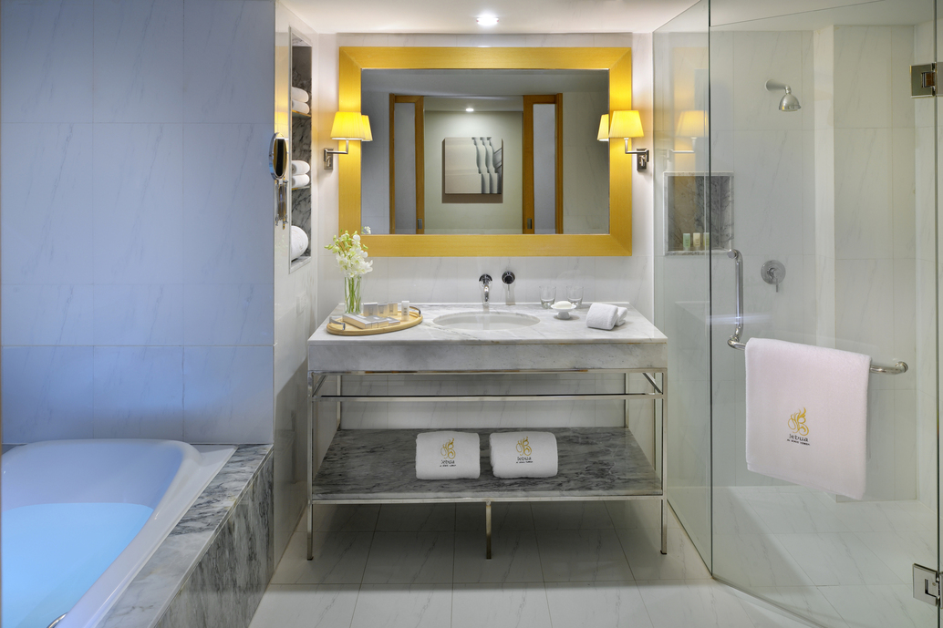 bathroom with centered mirror and marble sink bathtub on left side and shower on right side